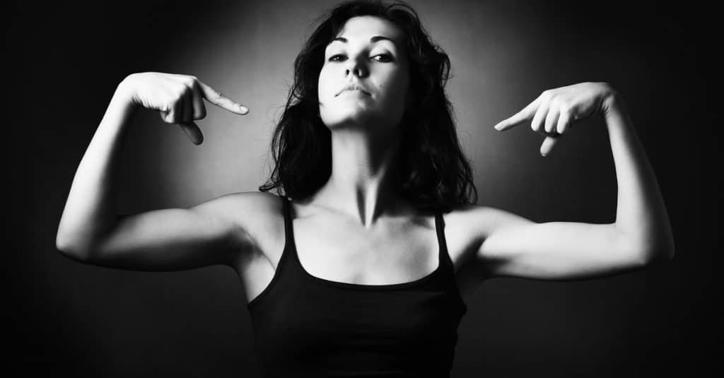 woman demonstrating her muscles and pointing to herself