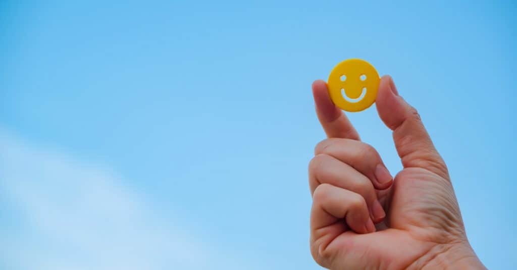 woman hand holding yellow emoticon smiley face