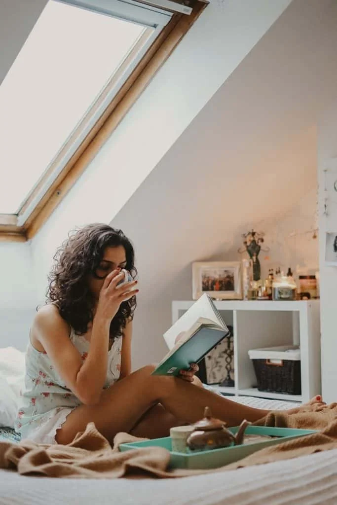 woman sipping tea while reading a book