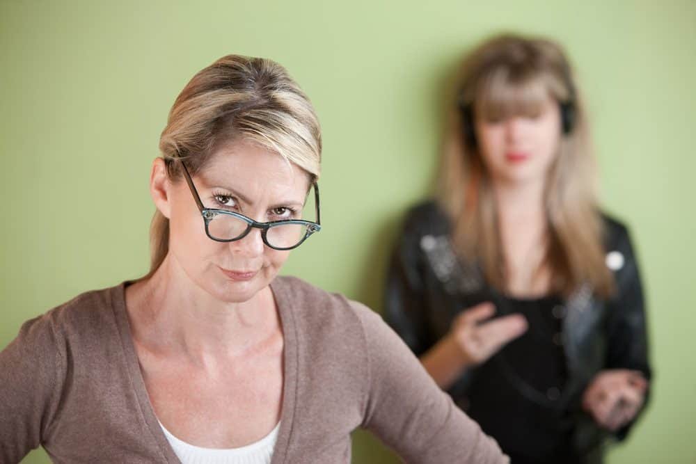 Daughter with on headphones behind suspicious mom