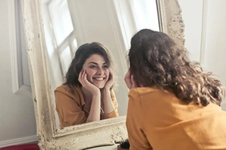 girl looking in mirror and smiling