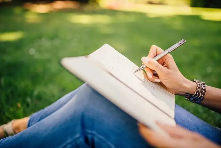 girl writing while sitting in garden