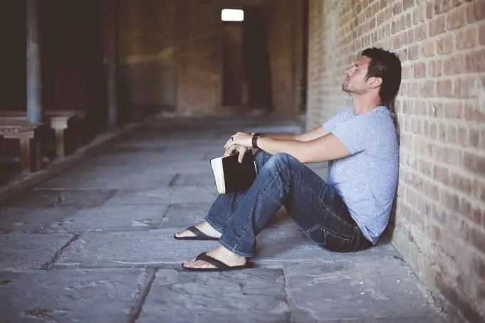 man sitting on floor with bible in hand