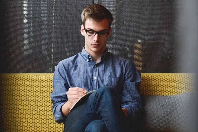 man writing on a notebook