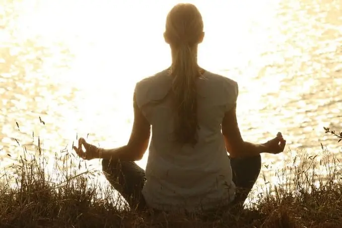 women meditating near lake