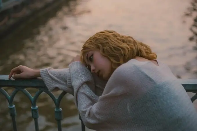 upset girl sitting near the lake