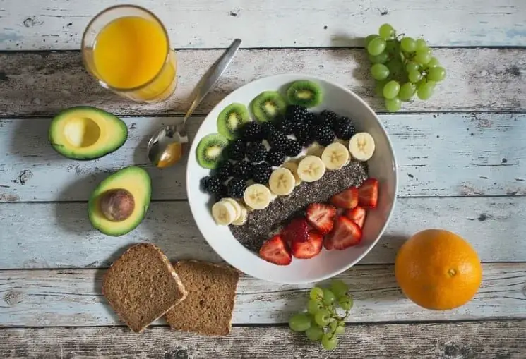 cup of smoothie with bowl filled with fresh fruits and seeds