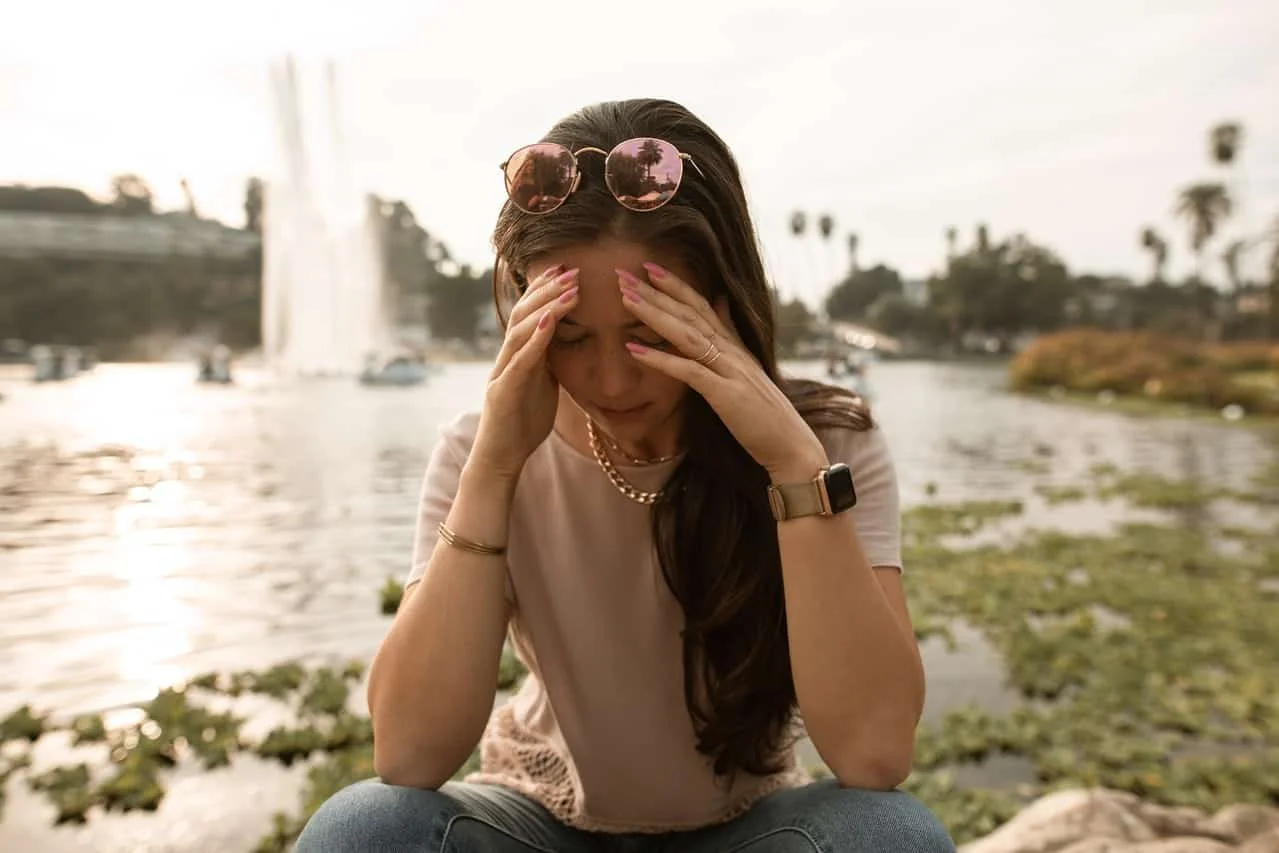 distressed woman sitting on lakeside during day time