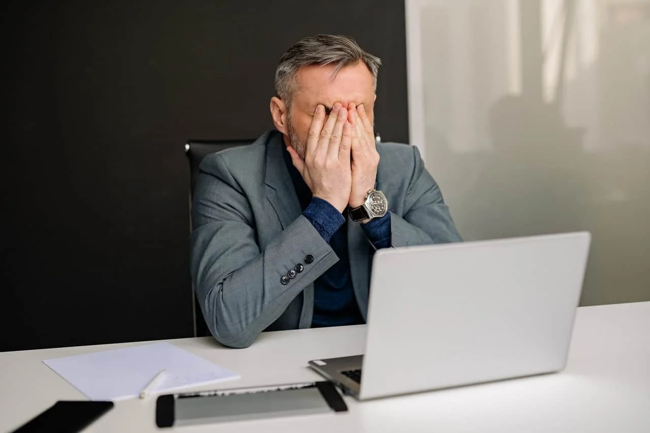 exhausted businessman covering face in his office