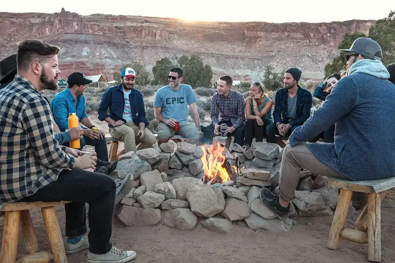 group of people sitting around fire flame during camping outdoor