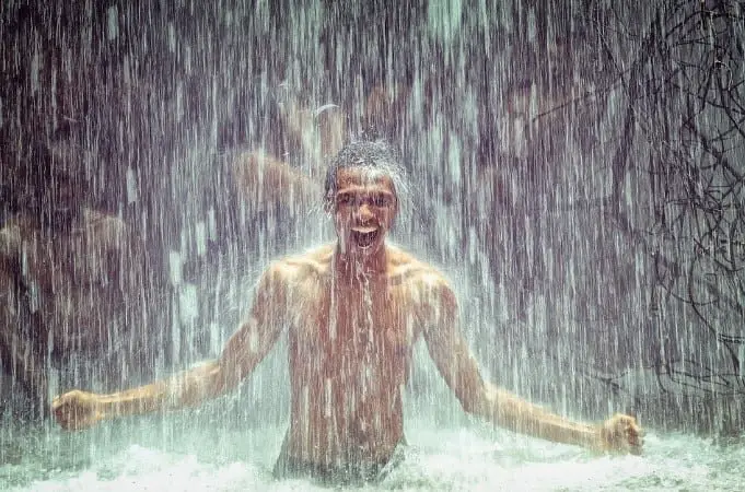 happy man bathing in a waterfall