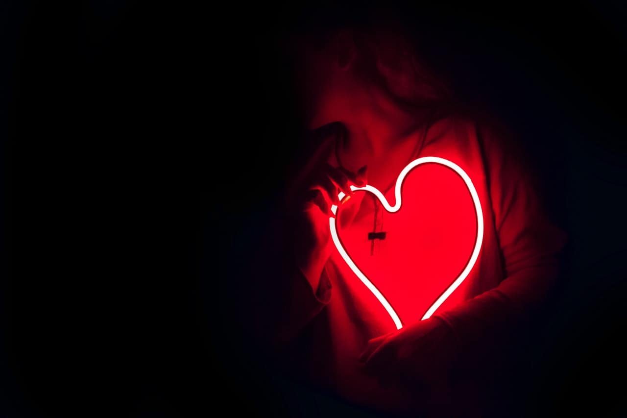 young girl holding red color heart shaped sign