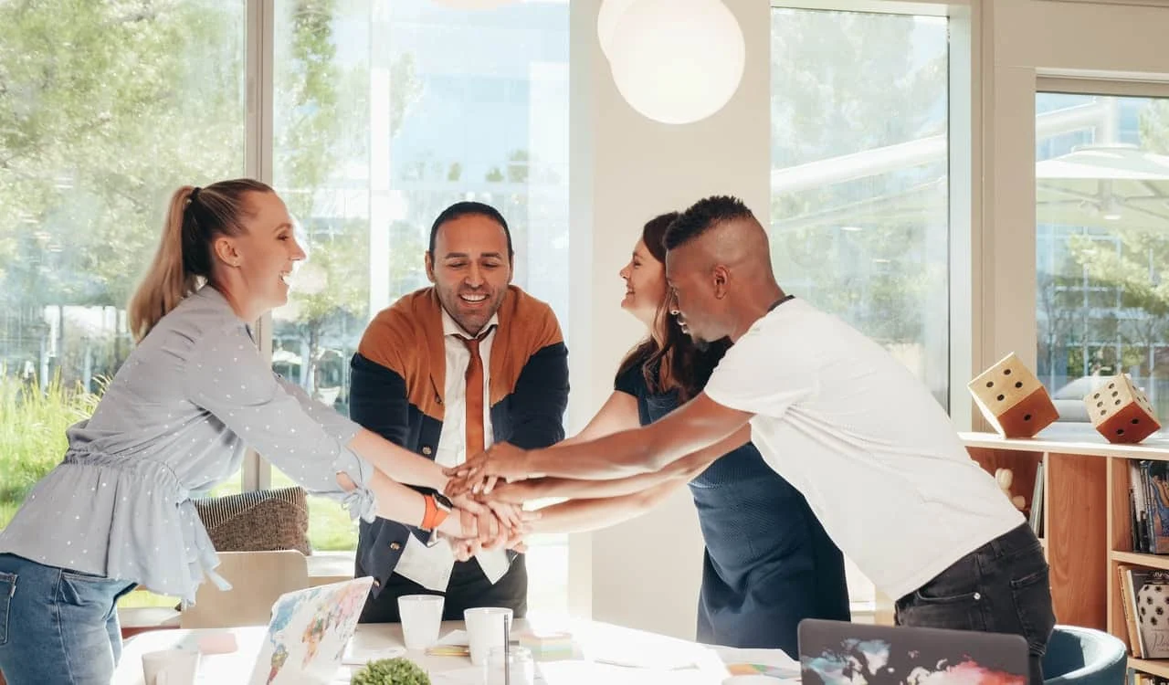 multiracial coworkers with hands together in office