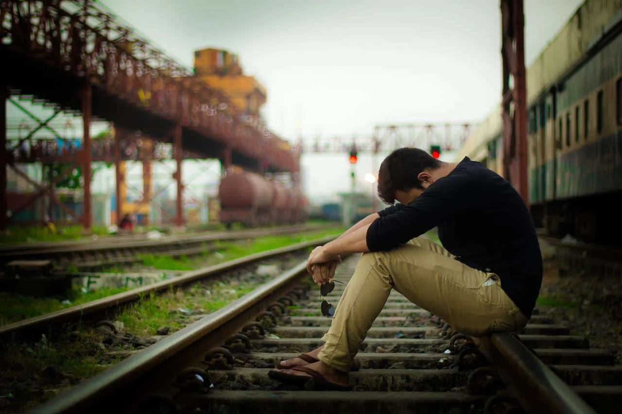 sad man sitting on railway track