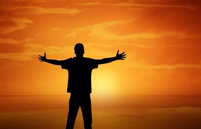 silhouette of a man with open arms in sunset background