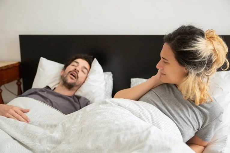 snoring man with disturbed partner in bed