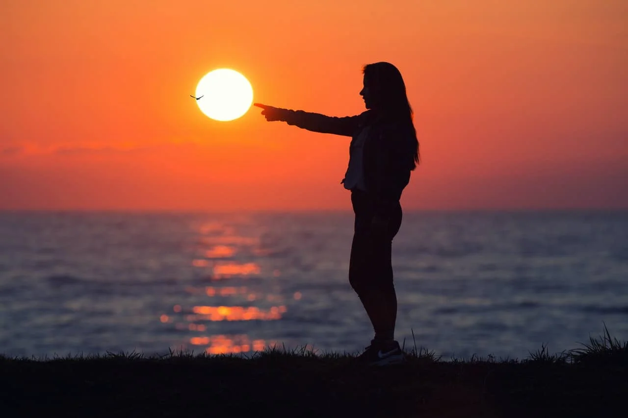 woman across sun during sunset