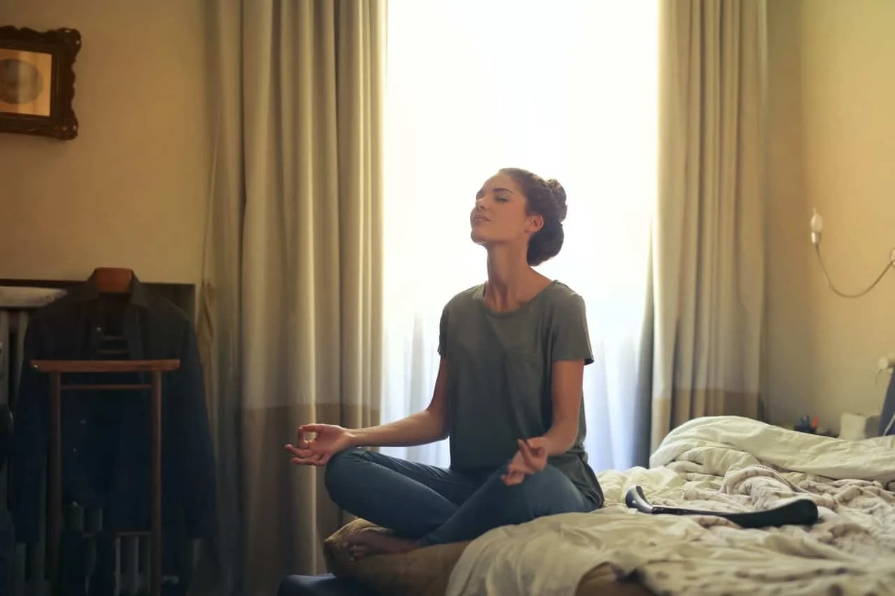 woman meditating in his bedroom during morning time