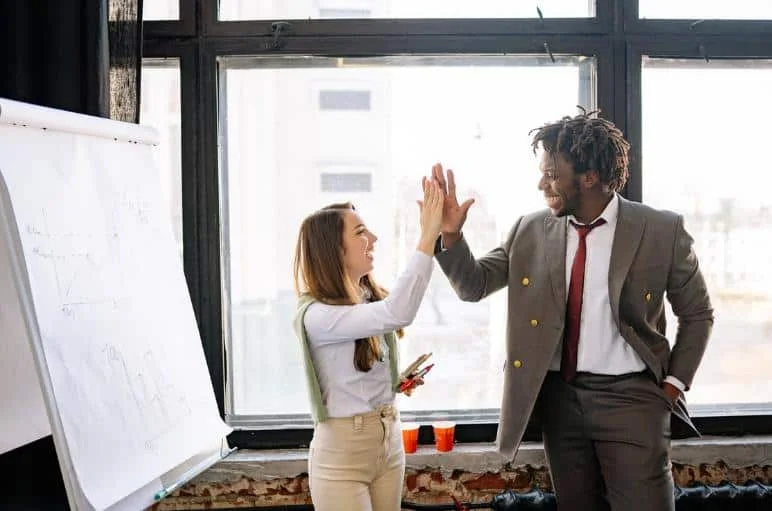 confident male and female coworkers doing high five