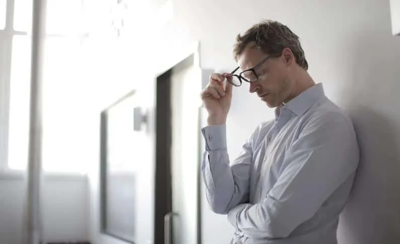 depressed man holding eyeglass