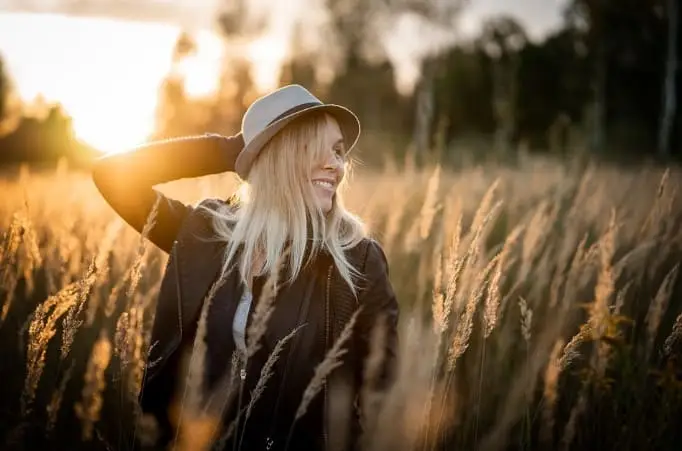 happy lady wearing a hat in a field