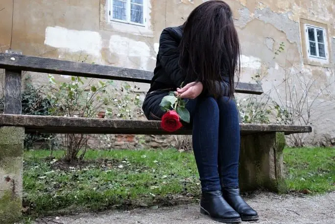 lonely woman on a bench holding a rose