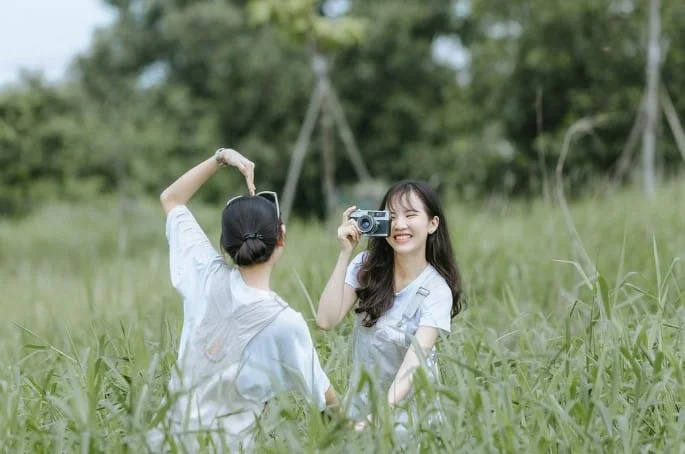 two female friends taking photos outdoors