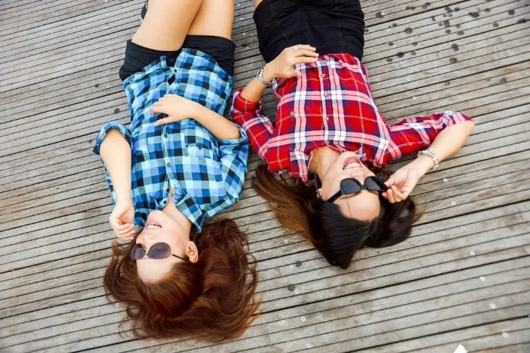 two women wearing dark glasses lying down