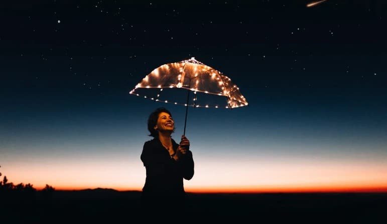 woman using a lighted umbrella at night