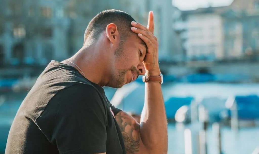 worried man holding his head in one hand