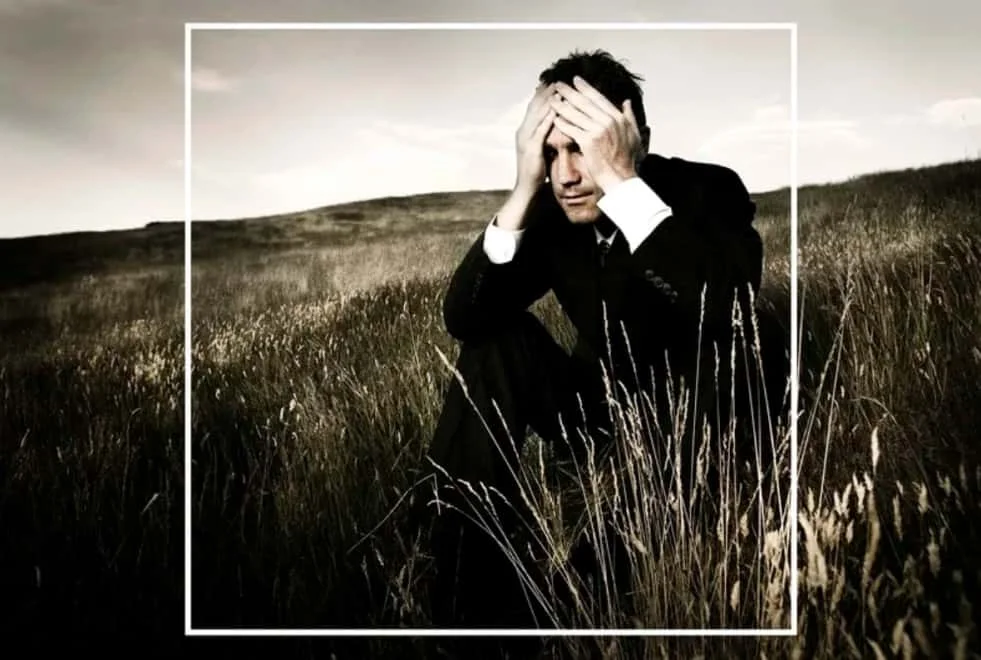 worried man in a suit sitting on a grass field