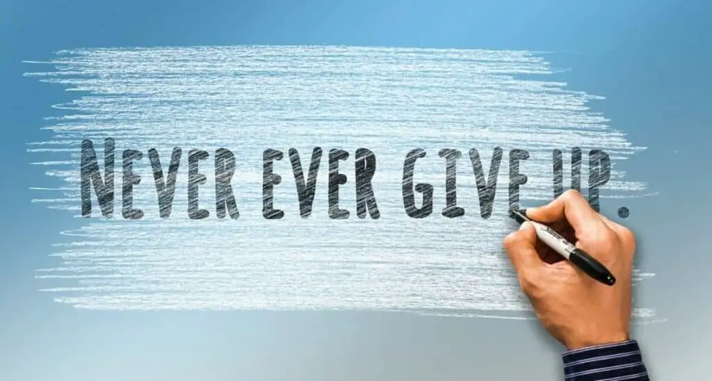 hand holding a pen on a “never ever give up” background