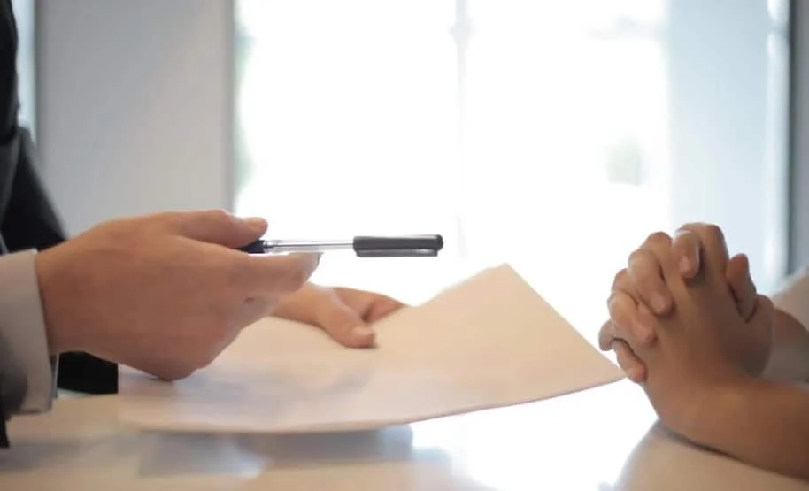 businessman handing a pen and paper to a client