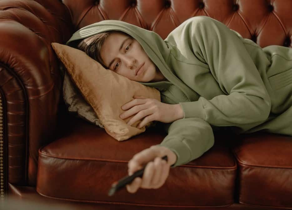 man holding a remote and lying on a couch