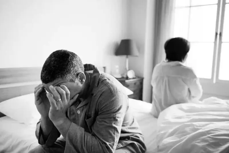 unhappy married couple in a bedroom with backs to each other