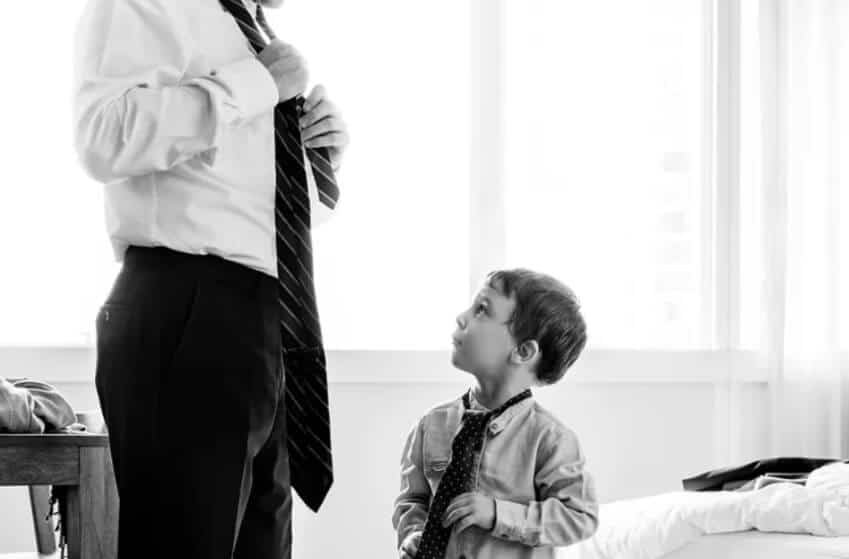 father teaches his son to tie a tie