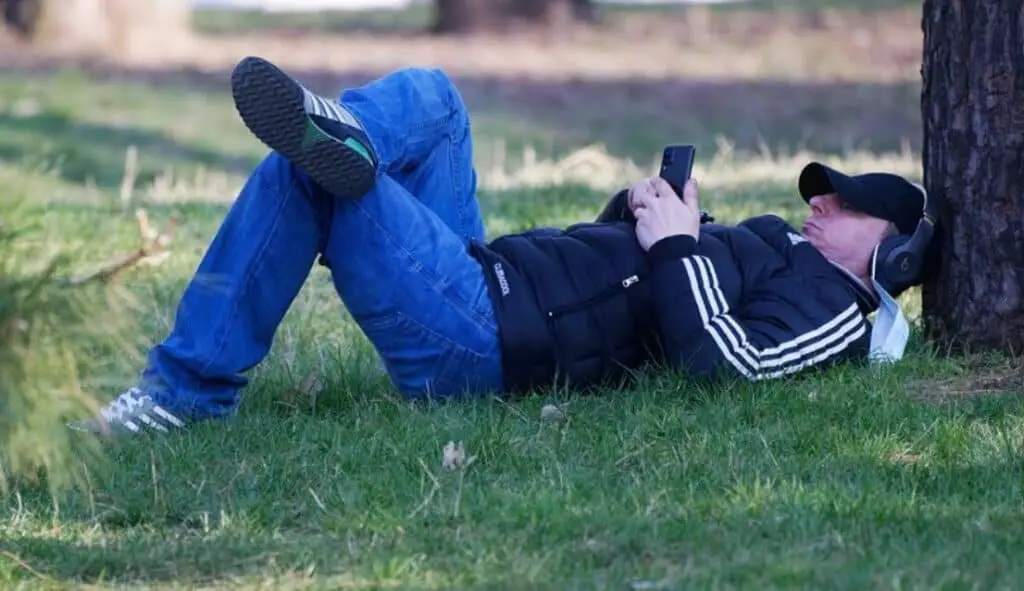 man laying in garden and listening music