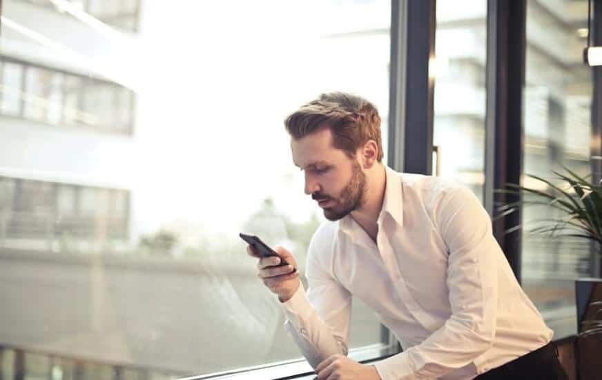 man using smartphone near window