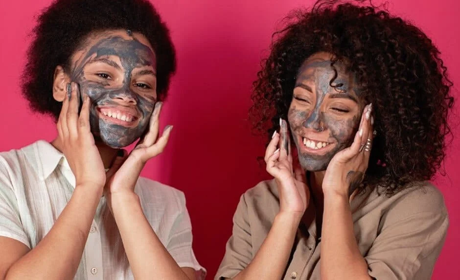 two ladies rubbing face masks on their faces