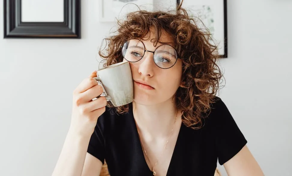 woman in deep thought while holding a coffee mug