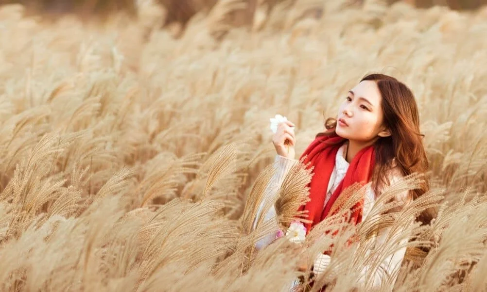 woman with red scarf in a field of reeds