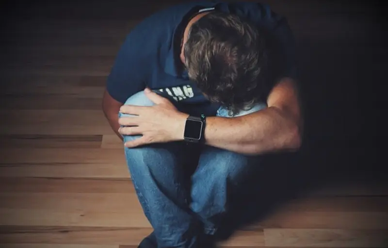 depressed man sitting on wooden floor