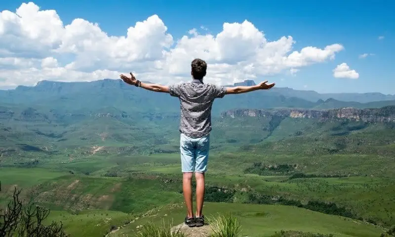 man standing on a rock and looking at the mountains