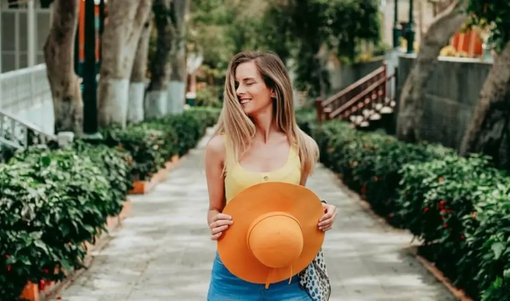 smiling woman with eyes closed holding a hat