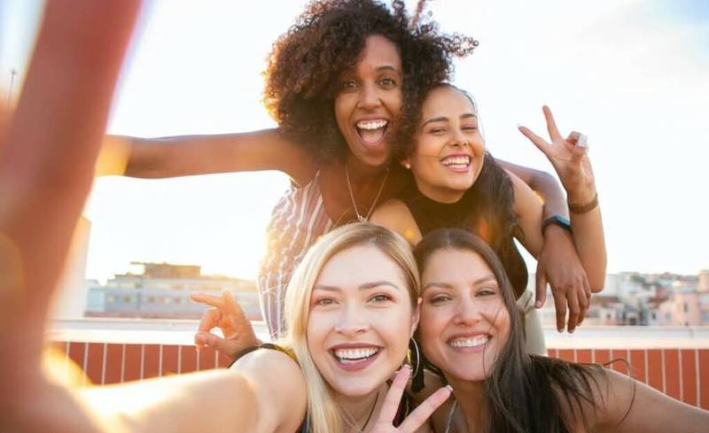 cheerful friends doing the peace sign