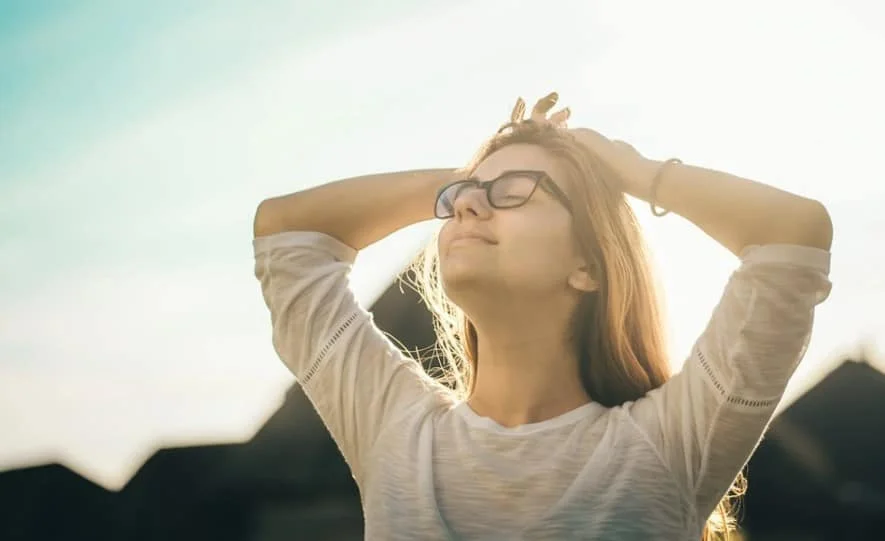 woman facing upward with eyes closed and hands on the head