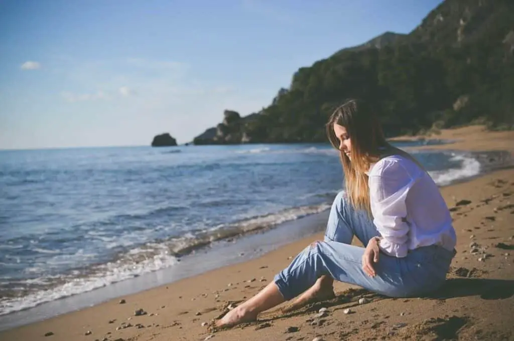 Barefooted woman sitting by the seaside