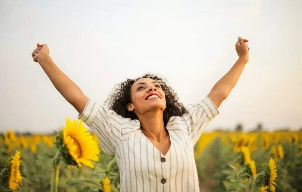 Woman raising hands in sunflower field