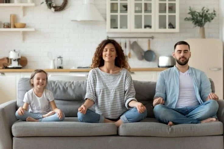 A family doing meditation on the couch