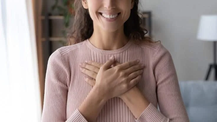 Woman holding both hands over her chest